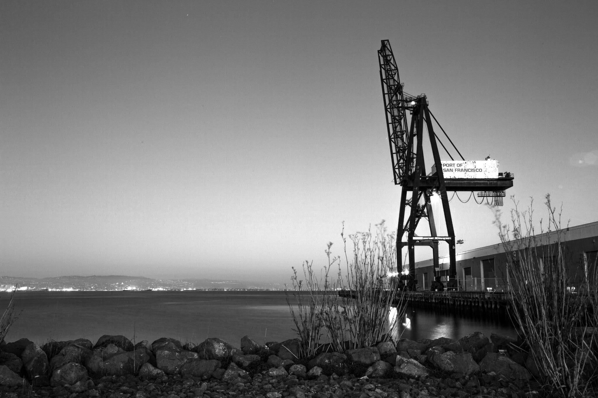 Harbor crane at waterfront against moody sky