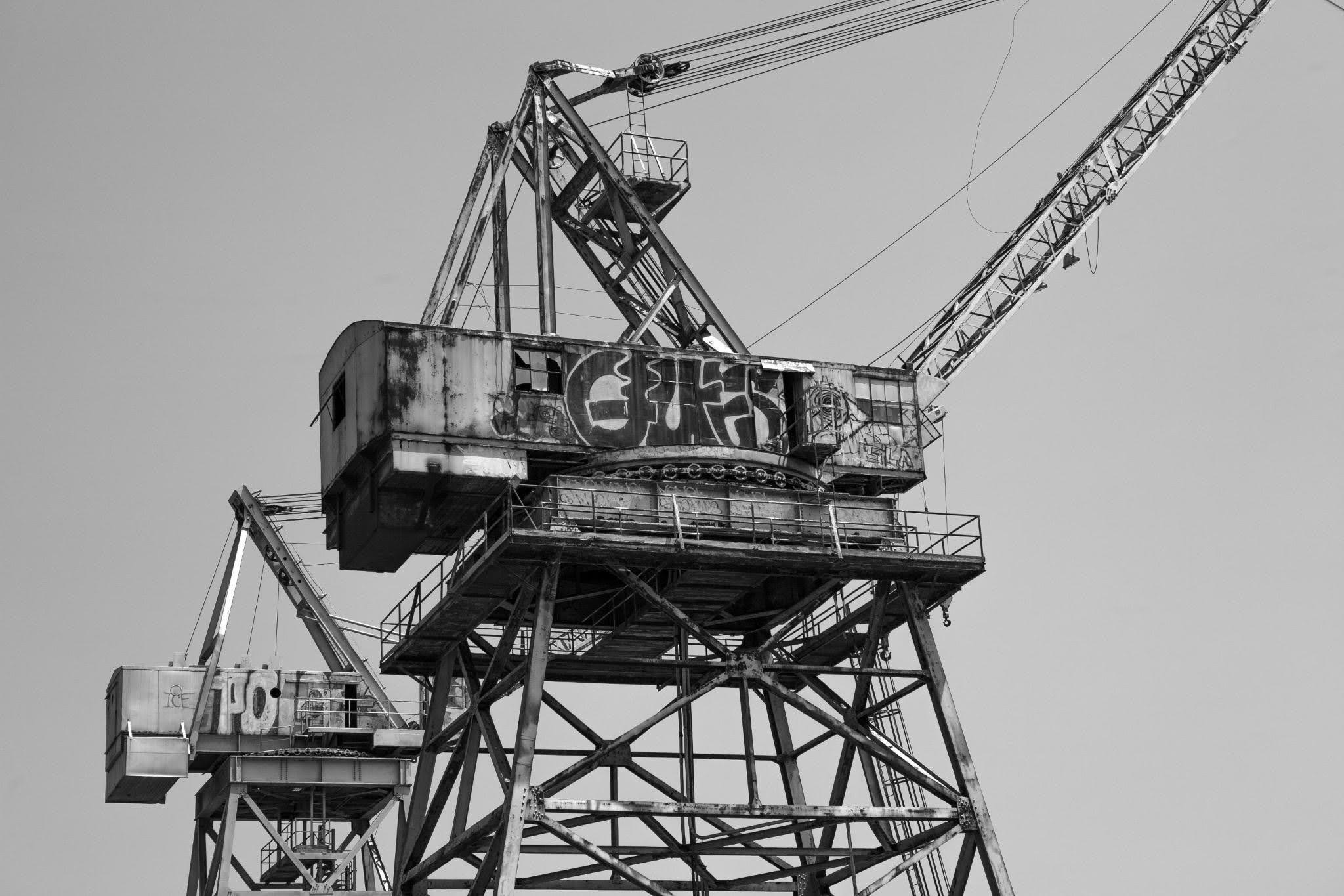 Industrial crane boom against empty sky with graffiti markings
