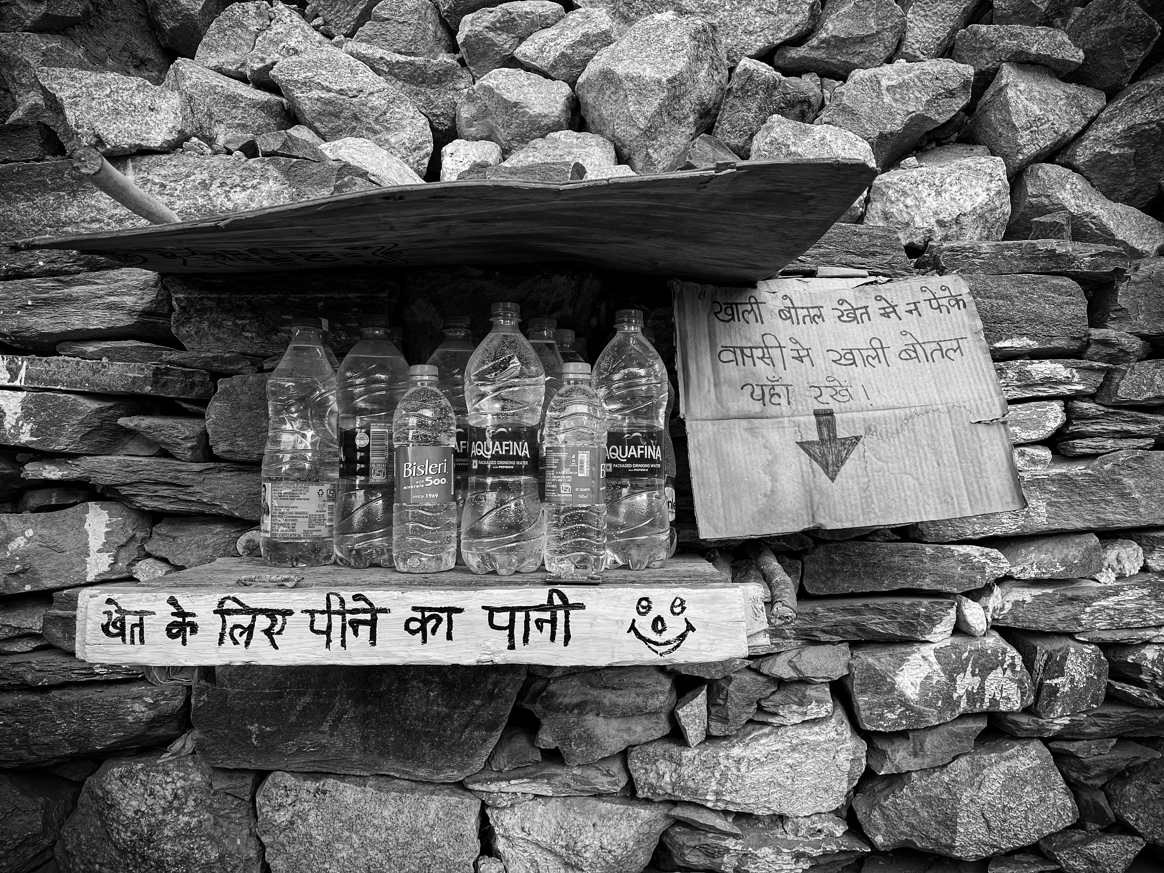 Stone wall with water bottles and Hindi script signage